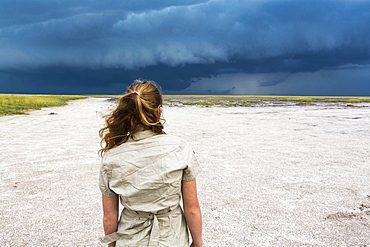 rear view of Thirteen year old girl looking at dramatic sky, Nxai Pan, Botswana