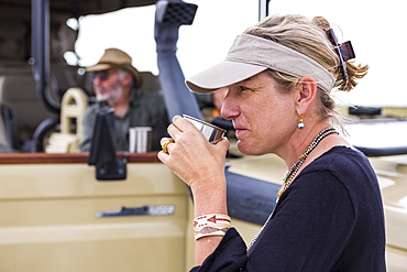 adult woman sipping coffee on safari, Nxai Pan, Botswana