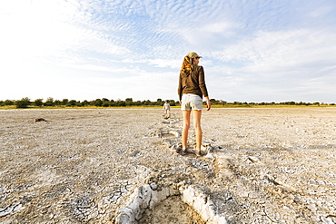 Thirteen year old girl leaping into elephant footprints, Nxai Pan, Botswana