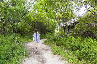 Thirteen year old girl walking on dirt path to tented camp, Maun, Botswana