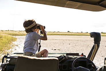 A six year old boy looking through binoculars across a salt pan