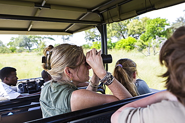 adult woman using binoculars in safari vehicle, Botswana