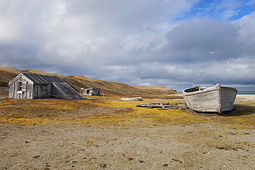 A small log cabin, a fishing hut with a beached boat, Svalbard, Norway