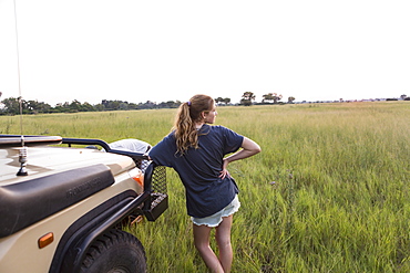 Thirteen year old girl leaning on safari vehicle, Botswana