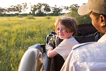 smiling Six year old boy steering safari vehicle, Botswana