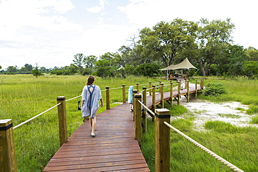 Thirteen year old girl walking on wooden path, tented camp, Botswana