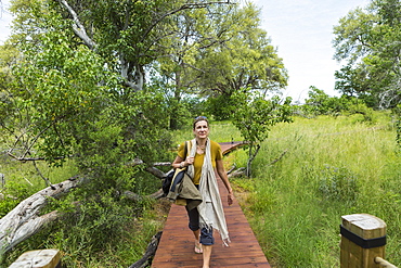 adult woman walking wooden path, tented camp, Botswana