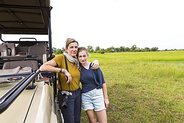 mother photographing with teen daughter near safari vehicle, Botswana