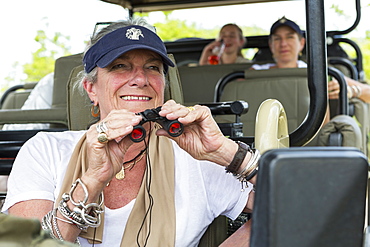 A family in a safari jeep in a wildlife reserve, a senior woman with binoculars, Okavango Delta, Botswana