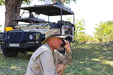 A guide in a bush hat on the radio at Moremi Game Reserve, Botswana