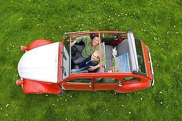 View from above of two people, a couple in a car with the roof open, Gloucestershire, England