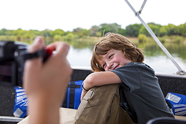 A five year old boy smiling at the camera on a river boat on the Zambezi River, Botswana