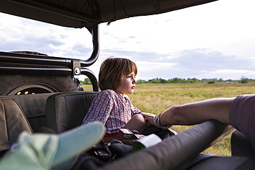 A five year old boy on safari, in a jeep in a game reserve, Botswana