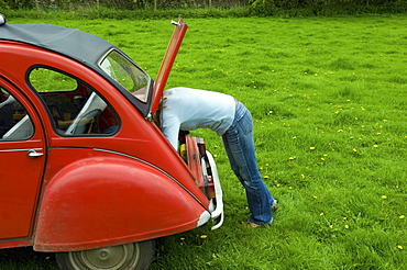 A person leaning in to the boot at the rear of the car, Gloucestershire, England