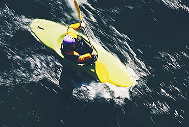 Overhead view of whitewater kayaker paddling rapids on a fast flowing river