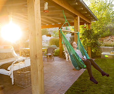 11 year old girl swinging in hammock at sunset