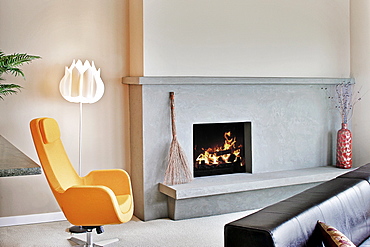 Living room in a modern house, with a fireplace and mantlepiece and hearth, and a modern yellow chair, Washington, United States