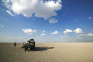 Man walking past 4x4 parked on the Makadikadi Salt Pans in Botswana