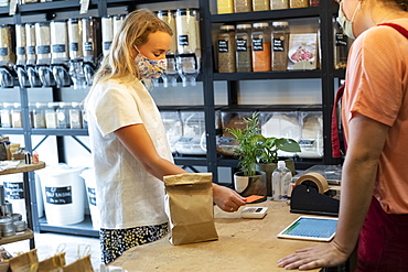 Woman wearing face mask shopping in waste-free local store, sustainability, Watlington, Oxfordshire, United Kingdom