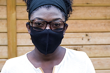 Portrait of black woman wearing glasses and face mask, looking at camera