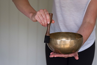 Woman on a couch, and a female therapist using Tibetan singing bowl, sound therapy