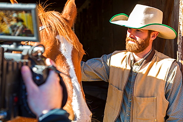 Cowboy with horse being filmed on ranch, British Colombia, Canada