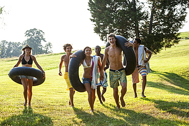 A group of young people, boys and girls, holding towels and swim floats, going for a swim, Maryland, USA