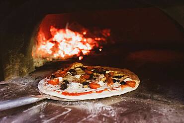 Close up of pizza in a wood-fired oven in a restaurant