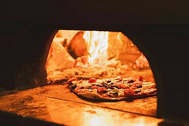 Close up of pizza in a wood-fired oven in a restaurant