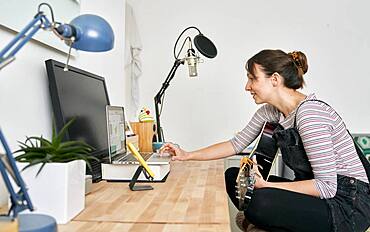 Woman using laptop for teaching guitar online