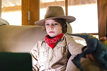 Young boy wearing safari outfit and headphones watching a movie on laptop