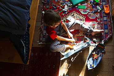 Overhead view of young boy in his room playing with his toys