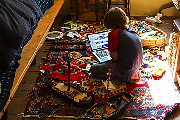 Young boy playing in his room, looking at laptop