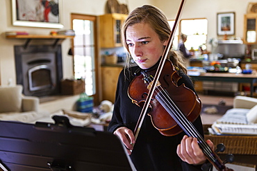 Teenage girl practicing violin at home