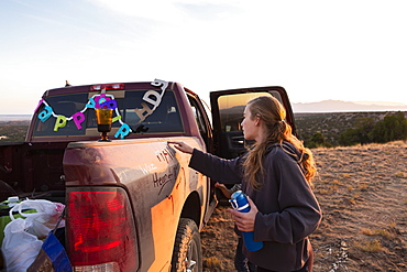 Teenage girl writing on the panel of an old pickup truck