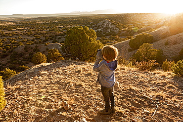 young boy in Galisteo Basin looking through binoculars at sunset