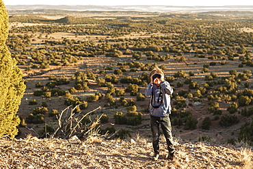 young boy in Galisteo Basin looking through binoculars at sunset