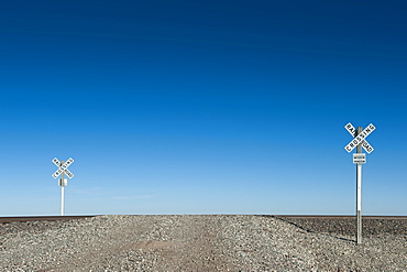 Railway crossing signs in desert landscape