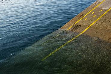 High angle close up of yellow footprints and lines painted on asphalt ground in a harbour.