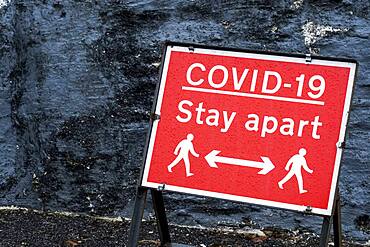 Close up of red and white Covid-19 distancing sign.