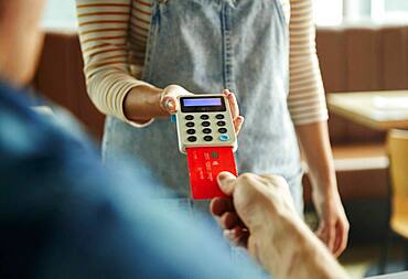 Woman holding contactless payment terminal for a customer paying by card