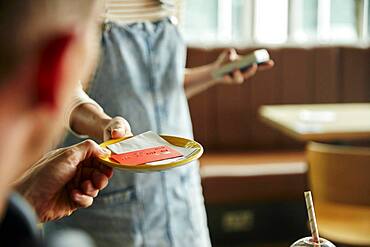 Woman holding contactless payment terminal for a customer paying by card