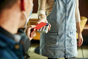 Woman holding contactless payment terminal for a customer paying by card