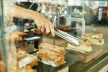 Close up of tongs selecting a slice of cake in cafe