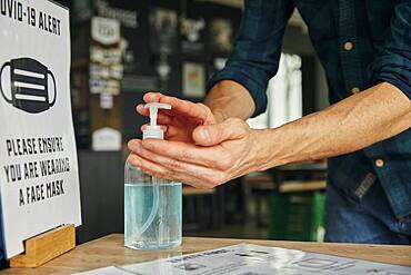 Man using hand sanitiser gel in restaurant