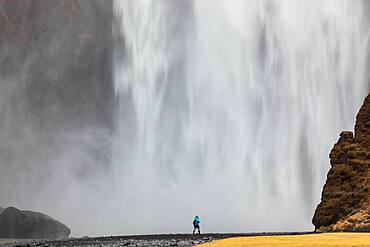 Skogafoss waterfall, man standing in front of a huge wall of water