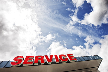 Auto service sign against partly cloudy blue sky viewed from below