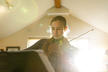 Teenage girl playing her violin in her bedroom