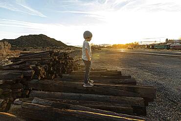 7 year old boy standing alone on railroad ties at sunset, New Mexico, United States of America