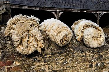 Close up of three bundles of sheepskin on a farm, Oxfordshire, United Kingdom